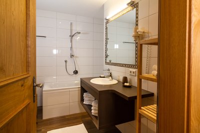 Badezimmer mit Badewanne, Waschtisch und Spiegel Apartment Tirol
