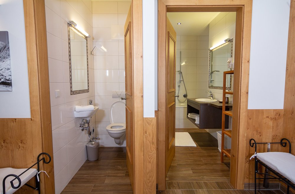 Badezimmer mit Badewanne, Waschtisch und Spiegel nebenan eine Toilette Apartment Tirol