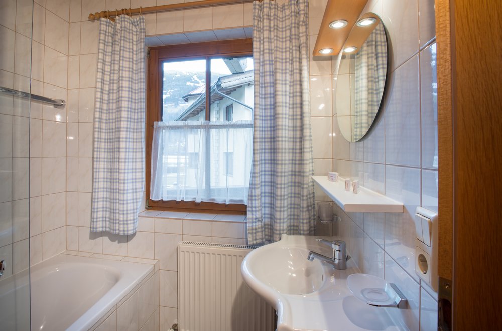Badezimmer mit Badewanne, Waschtisch und Spiegel Apartment Edelweiss