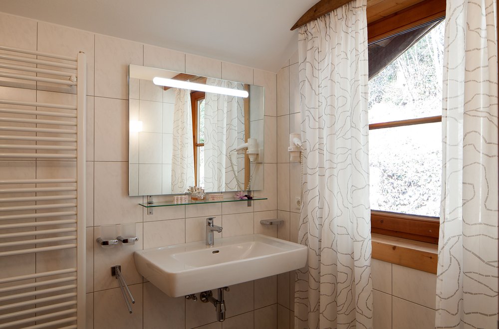 Badezimmer mit Sicht auf Waschtisch, Spiegel und Fenster Chalet Dorfbäck
